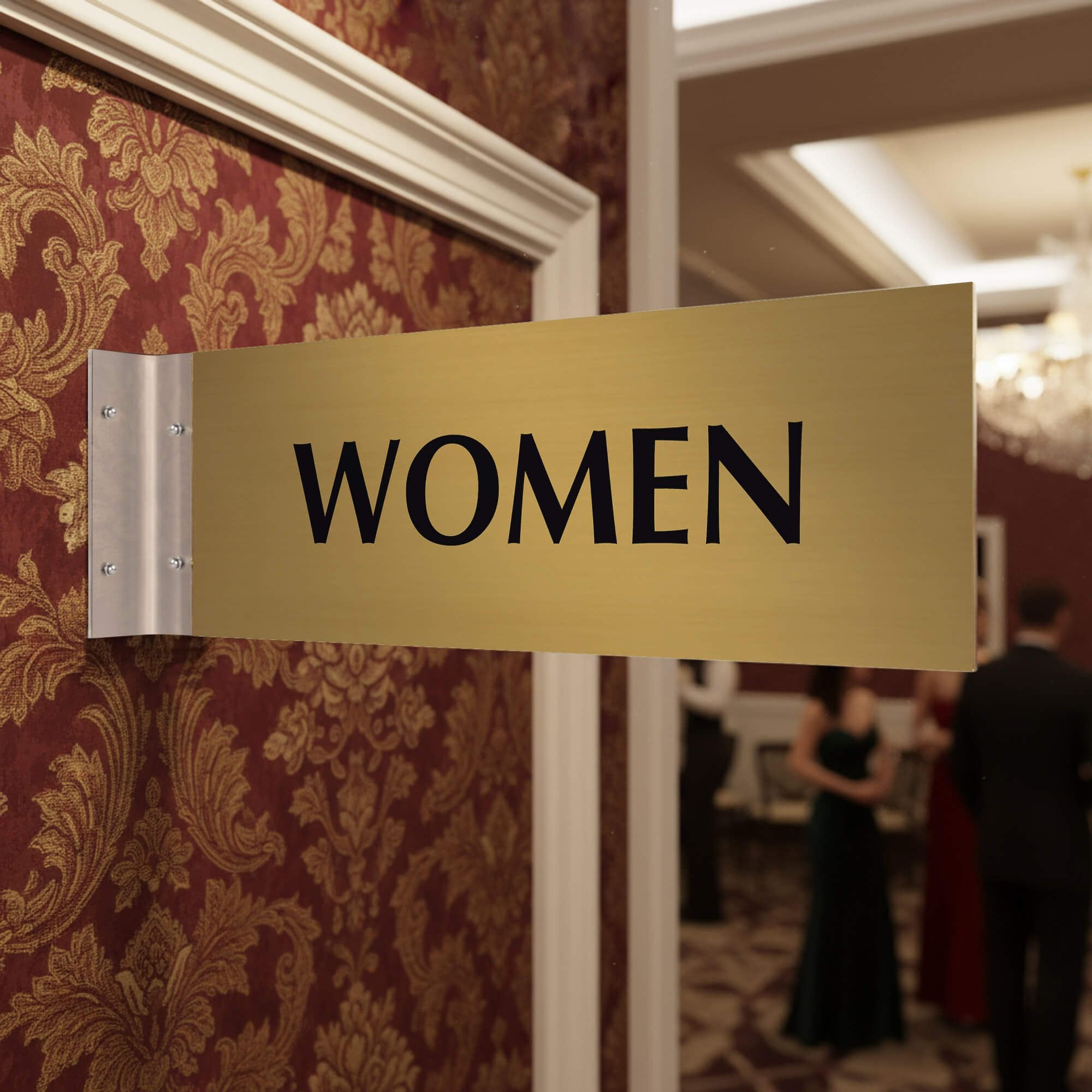 4” x 12” Corridor sign with gold material color, black engraved text, and silver holder on a hallway wall with text saying “WOMEN”.