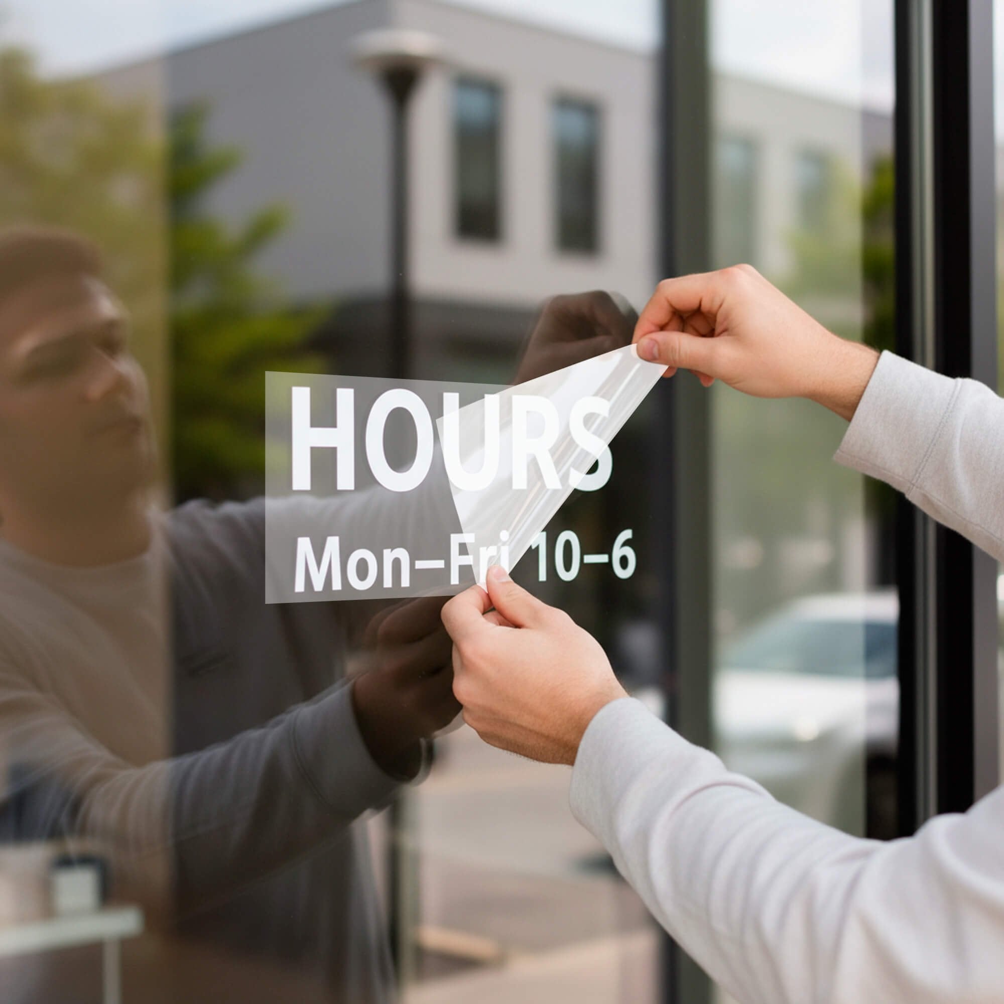 A man placing the vinyl decal on a window and peeling off the transfer tape