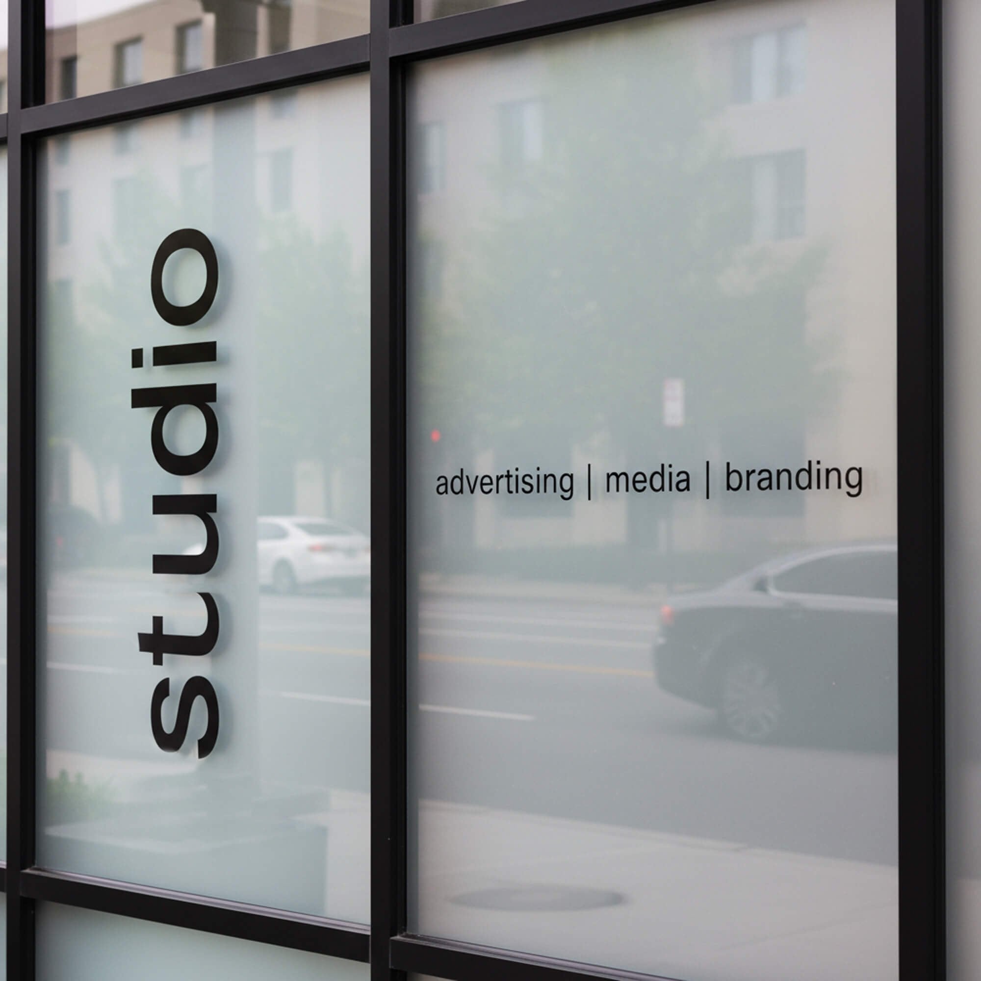 A black die-cut decal on the window of a studio