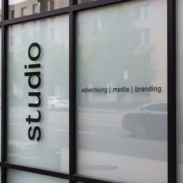 A black die-cut decal on the window of a studio