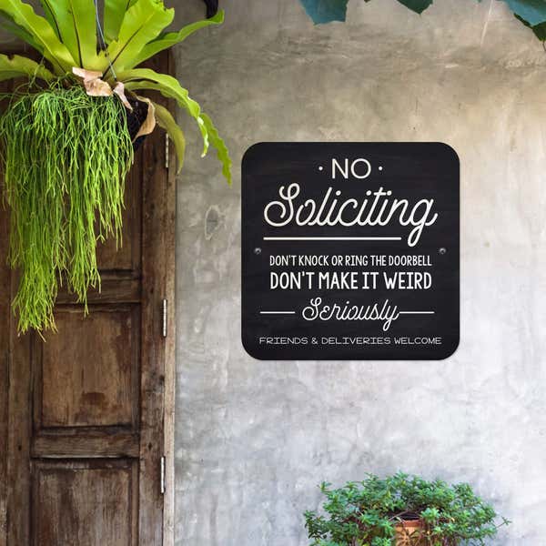 Black No soliciting. Don’t knock or ring the doorbell sign hung up on the wall.