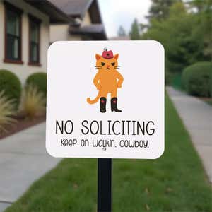 No soliciting cute cat sign reading, "keep on walking, cowboy” on a stake in the front yard