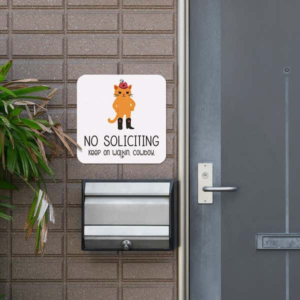 Cute orange cowboy cat no soliciting sign hung up next to the front door