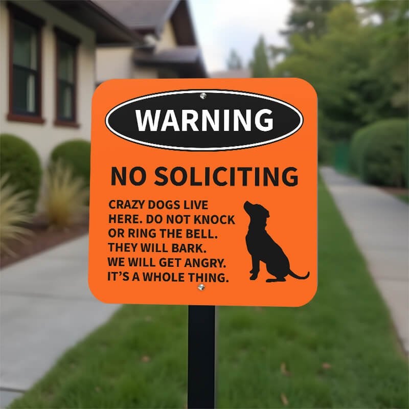 Orange no soliciting dog warning sign with dog icon with bold text reading “Crazy dogs live here” on yard stake