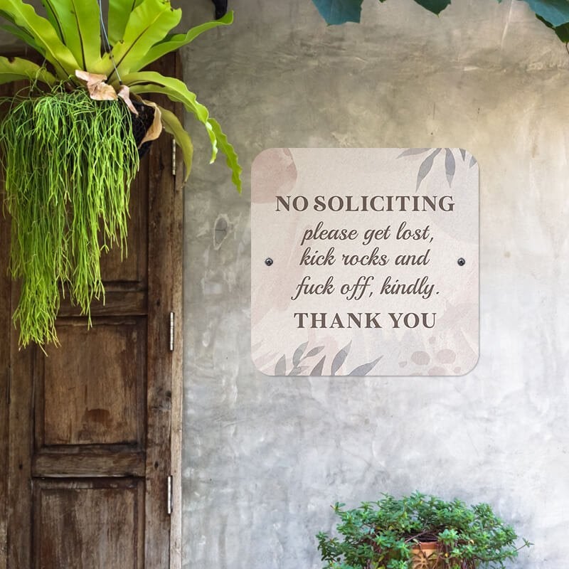 Pretty no soliciting sign hung up on a wall reading, "Please get lost, kick rocks, and f* off kindly. Thank you."