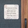 No soliciting sign on pastel floral background reading: Please get lost and kick rocks kindly, hung up on a wall.