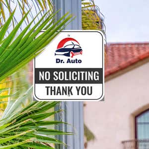 No soliciting sign with Dr. Auto car logo reading Thank you hung up on metal post