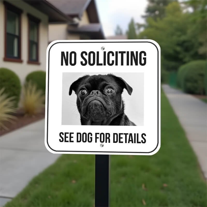 No soliciting sign with a custom pet photo of a black pug reading, "See dog for details" on a yard stake. 