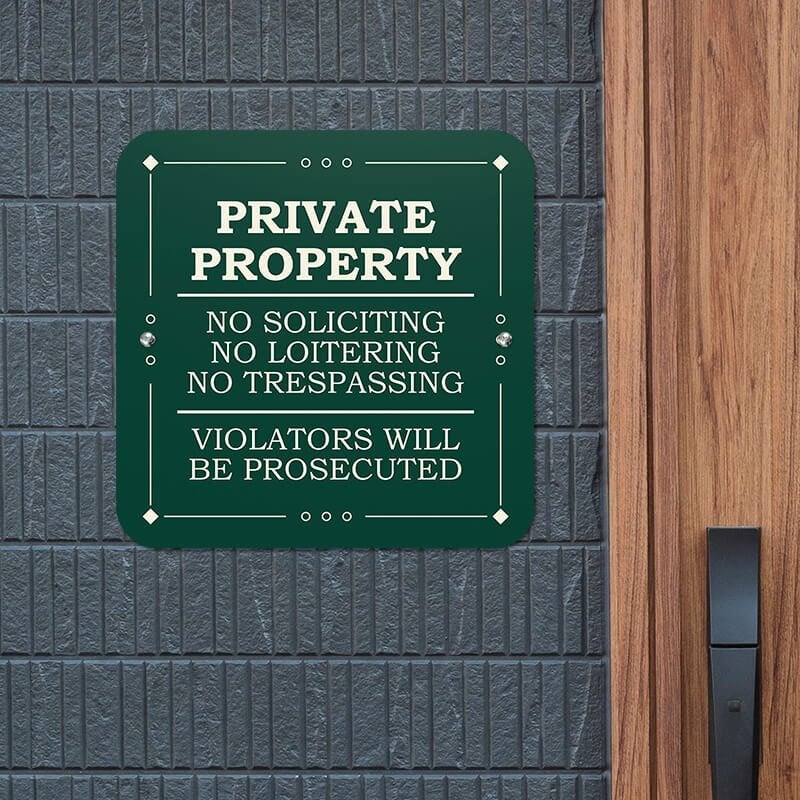 Green private property, no soliciting, no loitering, no trespassing sign reading Violators will be prosecuted hung on wall 
