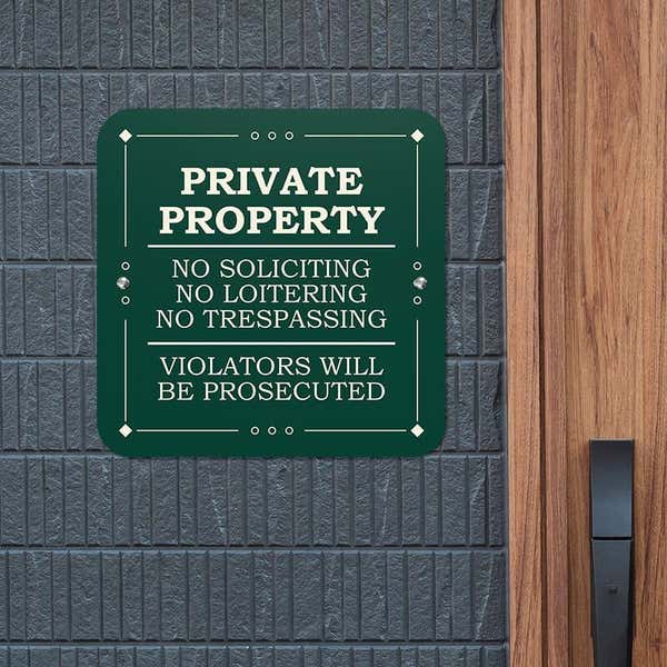 Green private property, no soliciting, no loitering, no trespassing sign reading Violators will be prosecuted hung on wall 