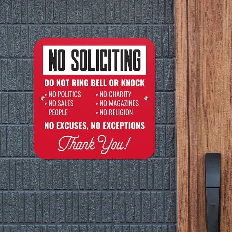 Red No soliciting sign in bold text. Do not ring bell or knock. No excuses, No exceptions in white text hung up on wall