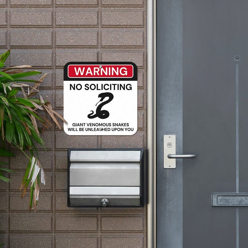 No soliciting warning sign, with a snake icon, hung next to the front door.