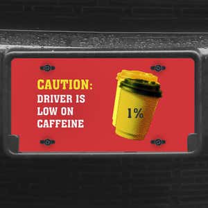 A close up of the Low On Caffeine front license plate on a black car