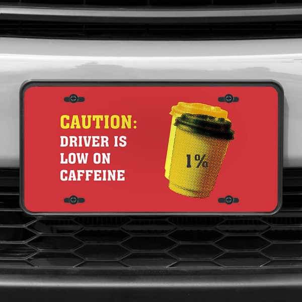 A close up of the Low On Caffeine front license plate on a white car