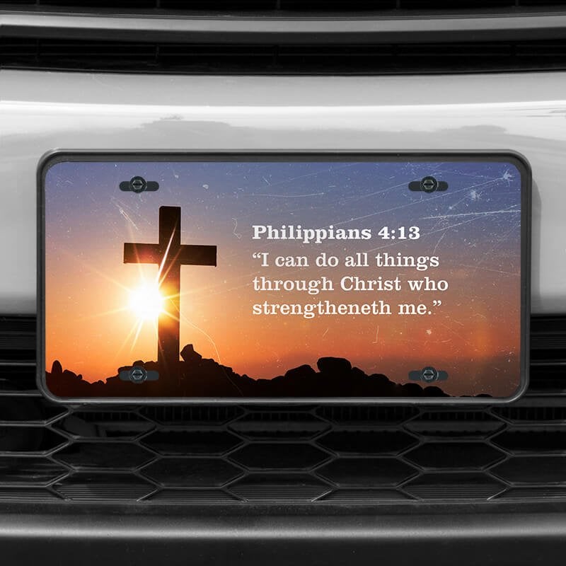A close up of the All Things Through Christ front license plate on a white car