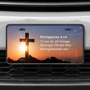 A close up of the All Things Through Christ front license plate on a white car