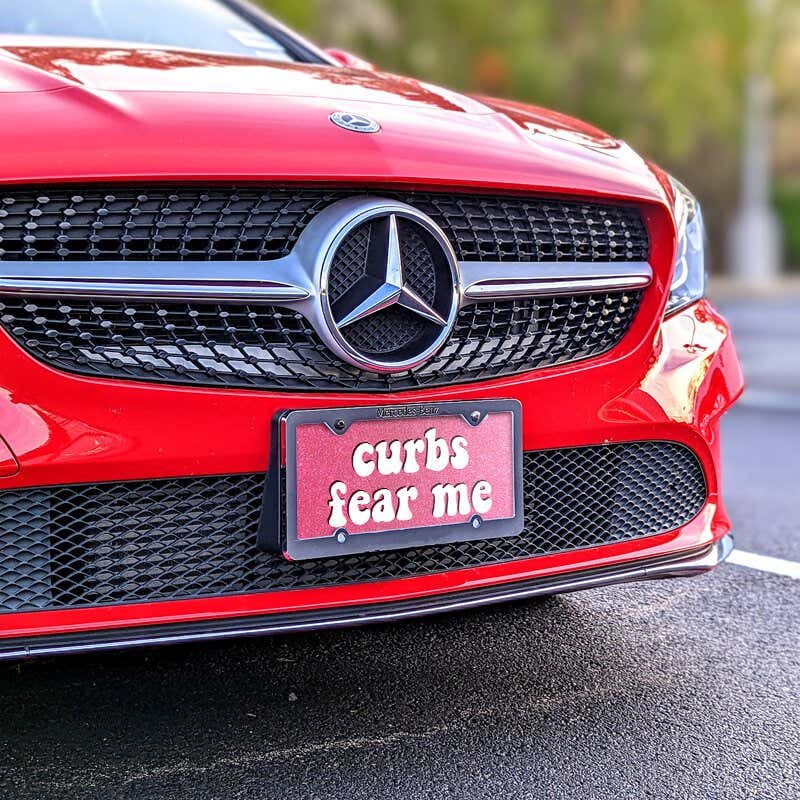 Curbs Fear Me front license plate on a red car