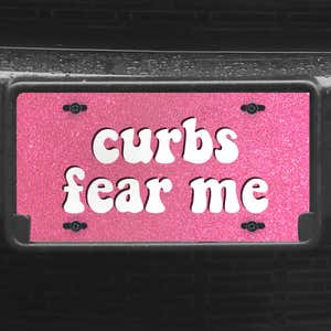 A close up of the Curbs Fear Me front license plate on a black car