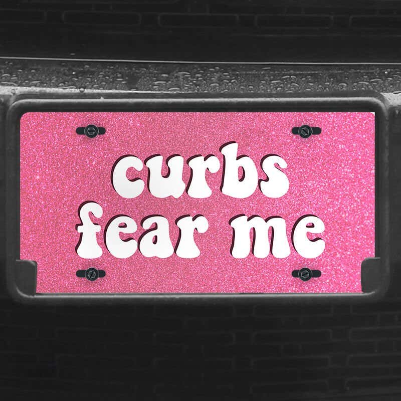 A close up of the Curbs Fear Me front license plate on a black car