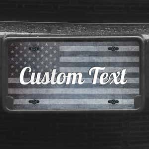 A close up of the Custom American Flag front license plate on a black car