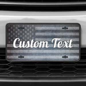 A close up of the Custom American Flag front license plate on a white car