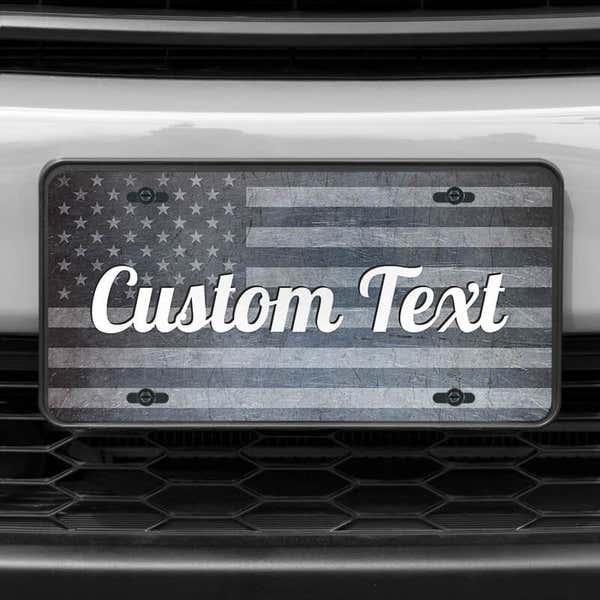 A close up of the Custom American Flag front license plate on a white car