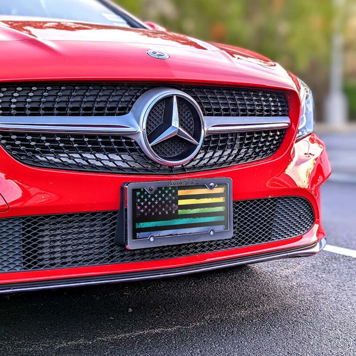 LGBTQ Pride American Flag front license plate on a red car