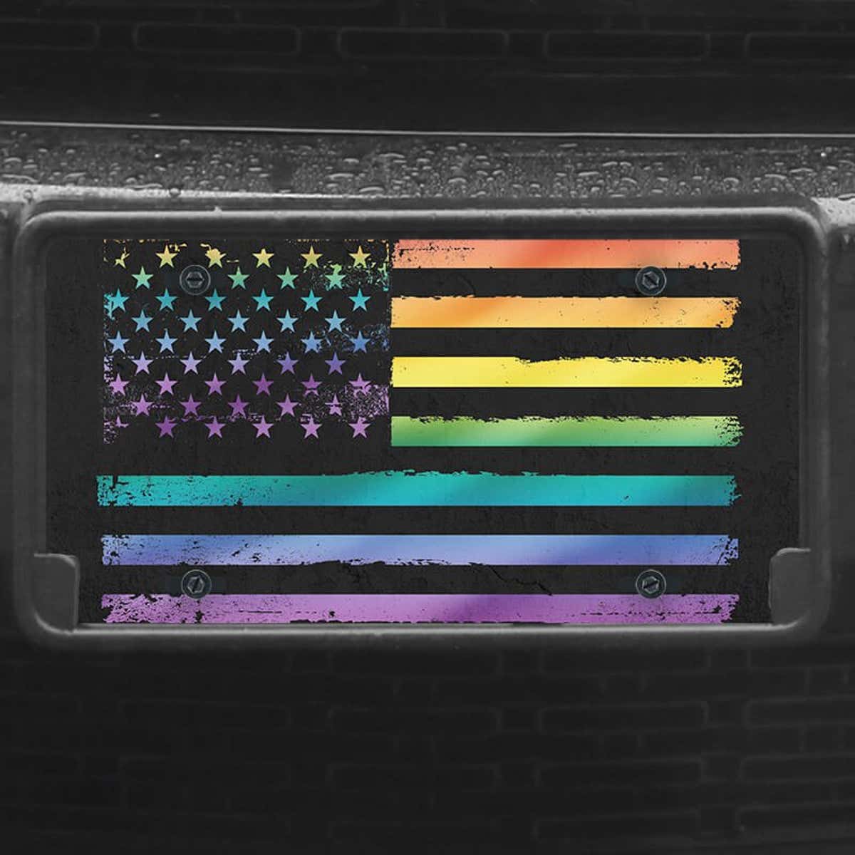 A close up of the LGBTQ Pride American Flag front license plate on a black car