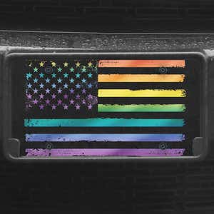 A close up of the LGBTQ Pride American Flag front license plate on a black car