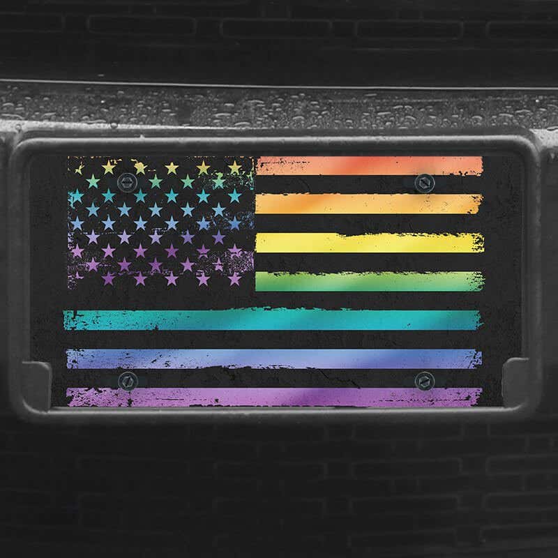 A close up of the LGBTQ Pride American Flag front license plate on a black car