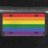 A close up of the LGBTQ Pride front license plate on a black car