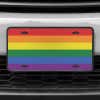 A close up of the LGBTQ Pride front license plate on a white car