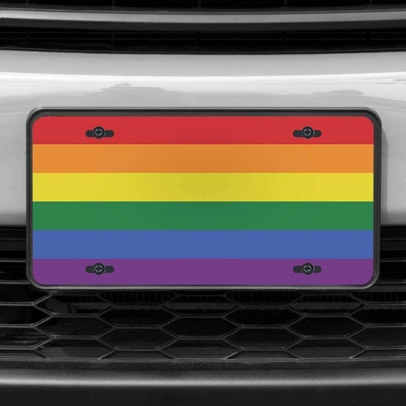 A close up of the LGBTQ Pride front license plate on a white car