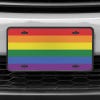 A close up of the LGBTQ Pride front license plate on a white car
