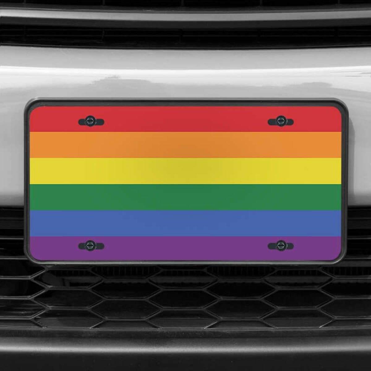 A close up of the LGBTQ Pride front license plate on a white car