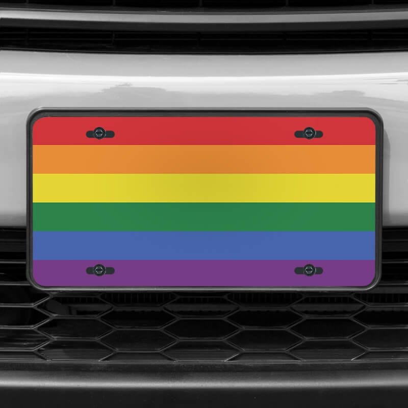 A close up of the LGBTQ Pride front license plate on a white car