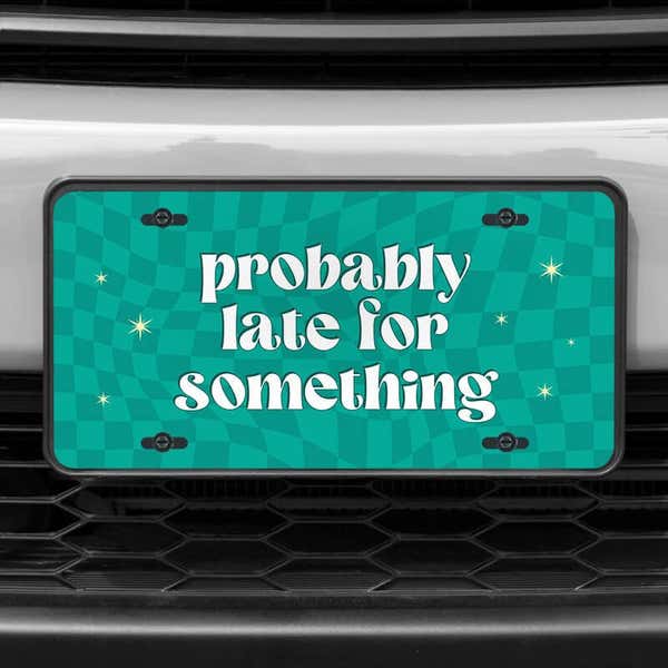 A close up of the Probably Late front license plate on a white car