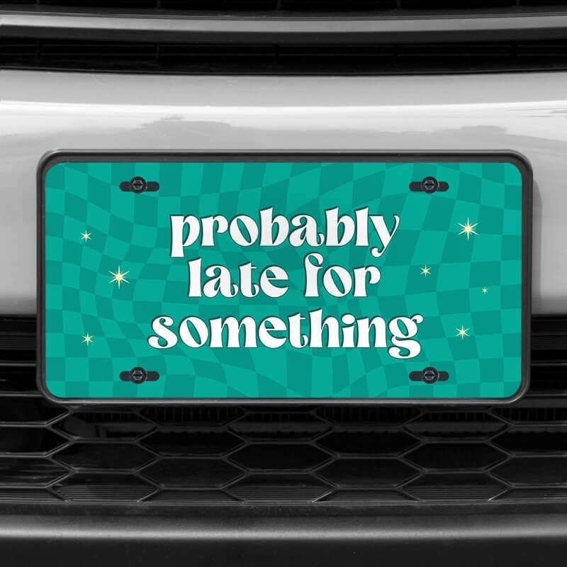 A close up of the Probably Late front license plate on a white car