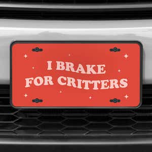 A close up of the I Brake For Critters front license plate on a white car