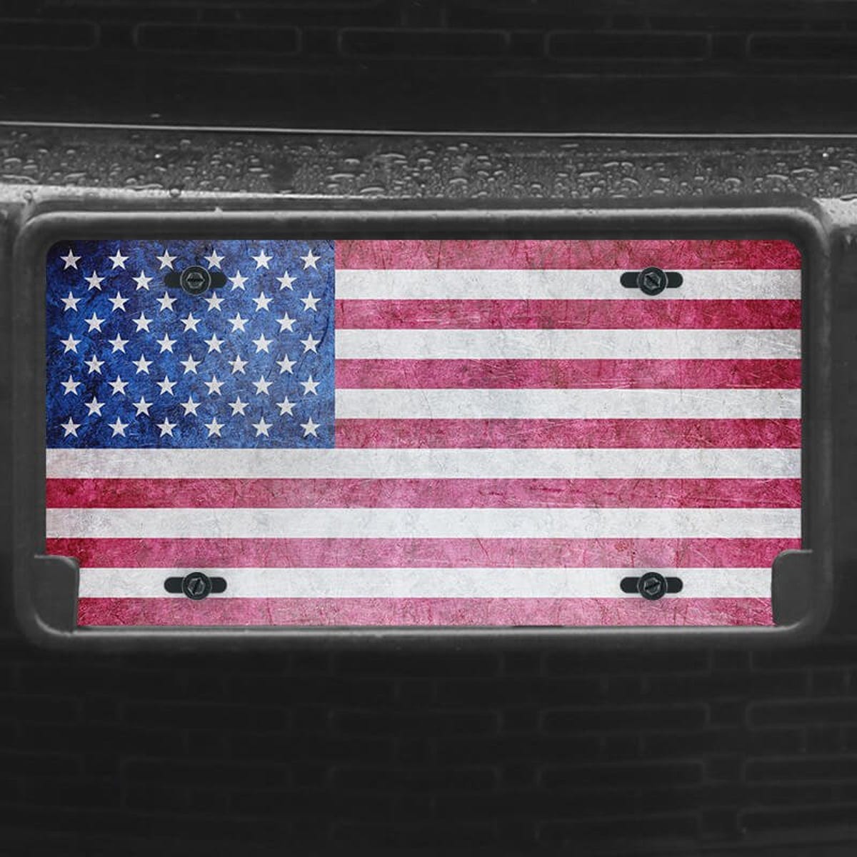 A close up of the American Flag Patriotic front license plate on a black car