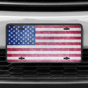 A close up of the American Flag Patriotic front license plate on a white car