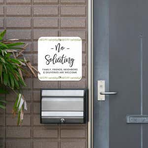Pretty no soliciting sign, with a floral design, hung outside next to the front door