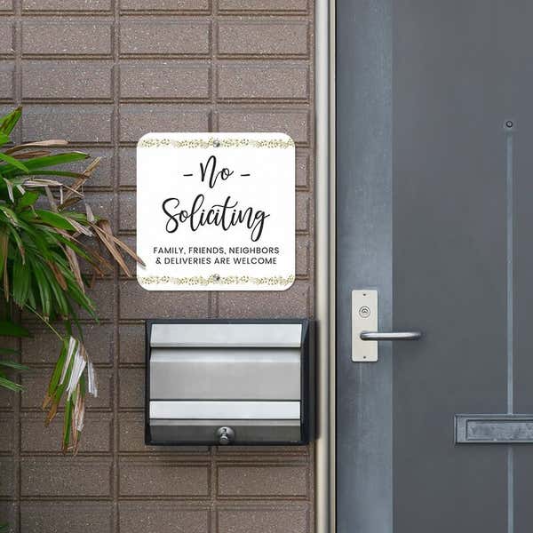 Pretty no soliciting sign, with a floral design, hung outside next to the front door