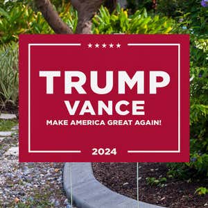 Trump Vance Red Yard Sign next to pavement