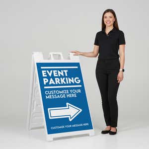 A woman standing next to an event parking A-frame sign with her hand on the top of the sign