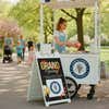 A grand opening A-frame sign placed next to a new ice cream cart
