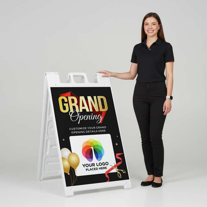 A woman standing next to the grand opening A-frame sign with her hand on the top of the sign