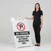 A woman standing next to the no parking sidewalk sign with her hand on the top of the sign