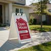 An open house sidewalk sign displayed on a sidewalk next to a house