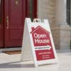 An open house sandwich board sign with custom information displayed outside of a house